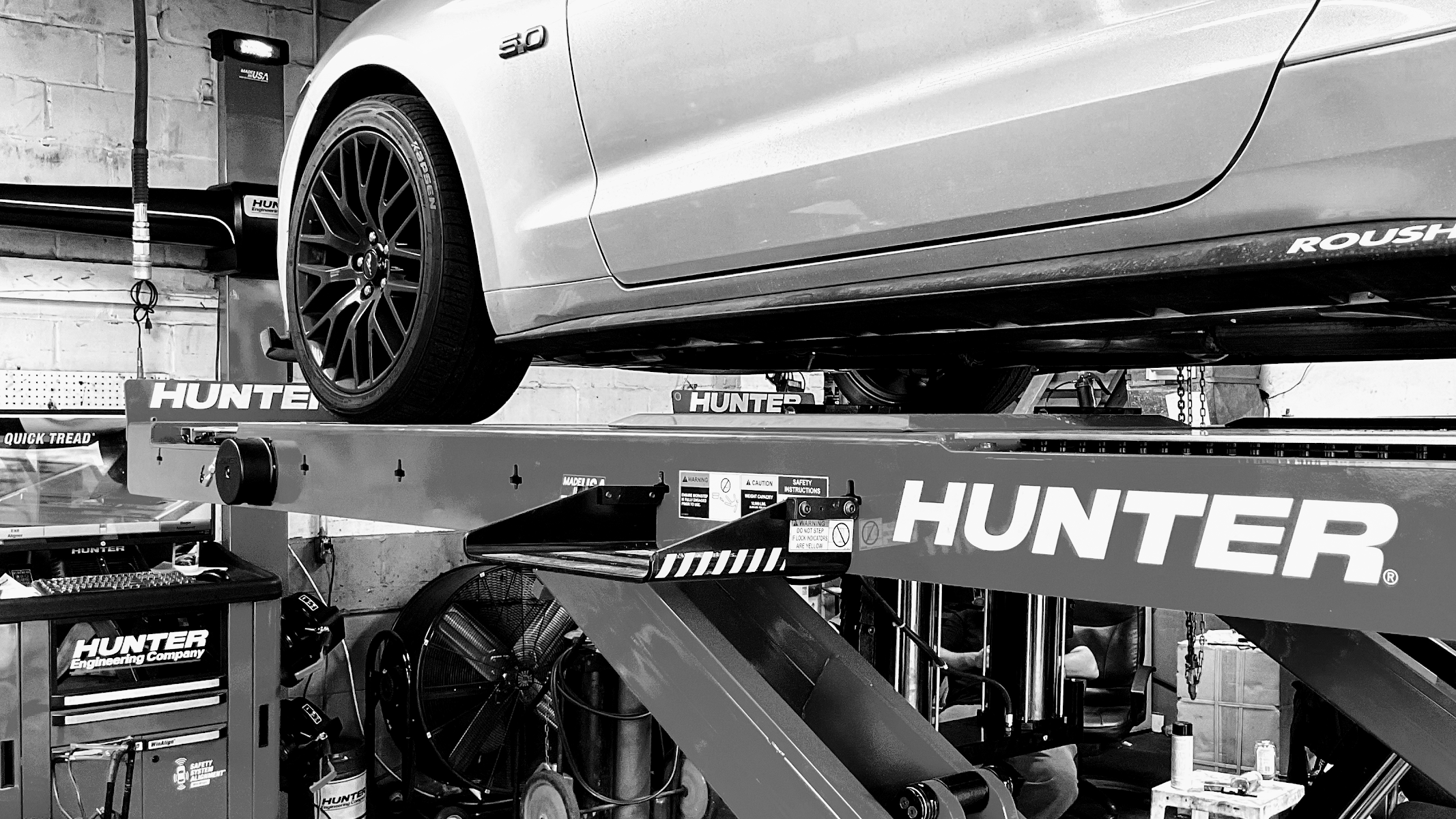 A car raised on the Hunter alignment rack inside the shop